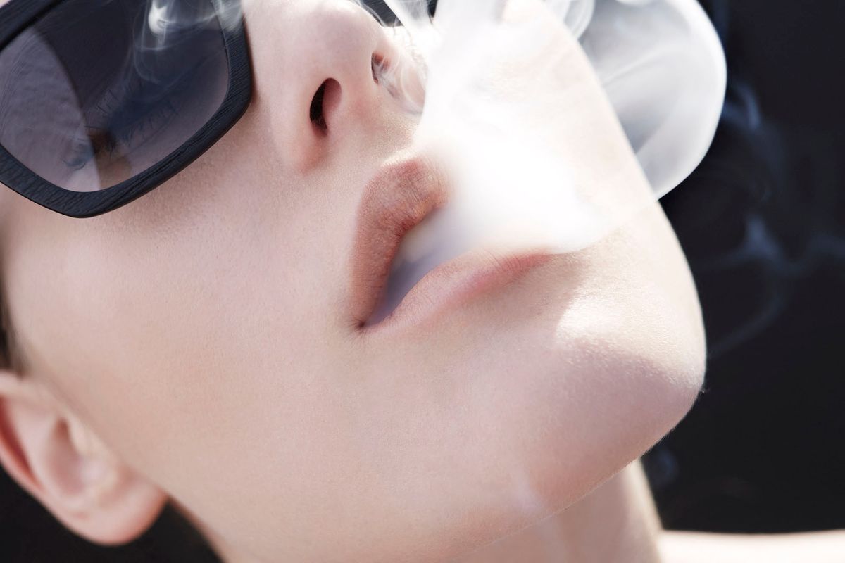 Studio head shot of young woman exhaling cigarette smoke (Photo by Franck Sauvarie / Cultura Creative / Cultura Creative via AFP)