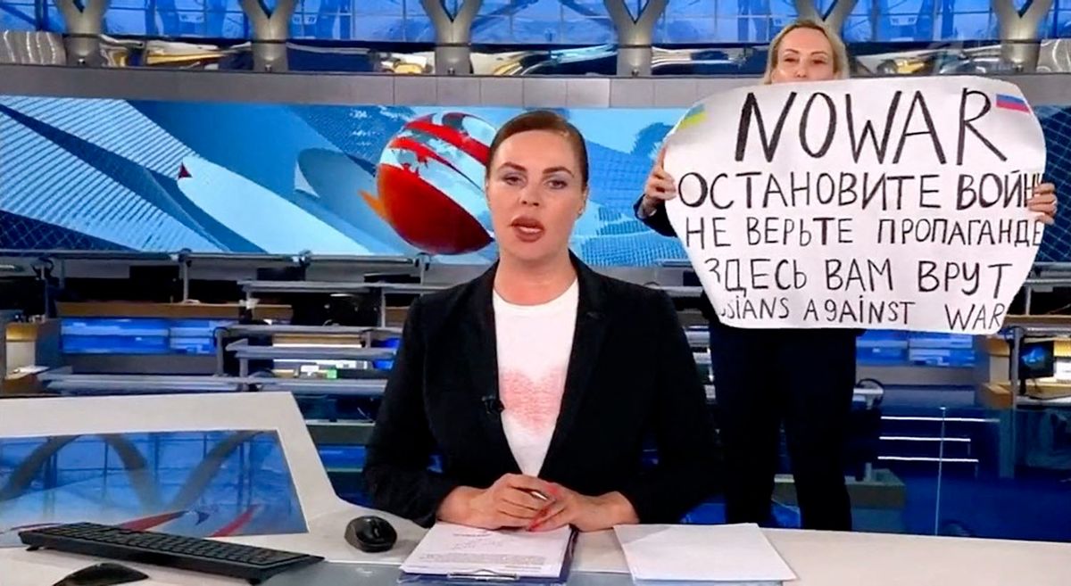 Editor Marina Ovsyannikova runs out behind the back of the news anchorwoman during on-air news on Monday March 14, 2022 evening prime time news program at the Russia state television Channel One with a placard which reads: Stop the war! Don?t believe propaganda! They?re lying to you here! The woman has been named as Marina Ovsyannikova, an editor at the channel. Channel One is the second most popular news channel in Russia. Ovsyannikova is believed to be in police custody after the protest. (Russia Channel One/EYEPRESS) (Photo by EyePress News / EyePress via AFP)