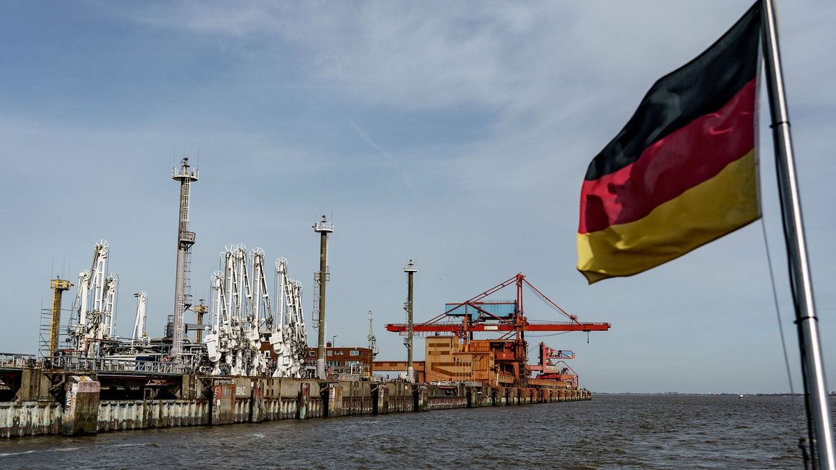 A german flag waves from the back of a ship in front of port facilities of the DOW Chemical Company, a global leader in the chemical business, at the industrial harbour of Stade, on the river Elbe in northern Germany, on April 12, 2022. - Germany lacks the infrastructure to absorb huge new supplies, with no liquefied natural gas (LNG) terminals along its coast where tankers can dock. Approval documents for a LNG terminal planned to open in 2026 at the industrial harbour of Stade will be submitted shortly. There are currently 37 LNG terminals across Europe, 26 of which are located in EU member states.The seaport and the large rock salt deposits in the region contribute to Stade being a strategically important location for the chemical industry. Dow produces in Stade around 4 million tons of basic and specialty chemicals for its own use and for international customers. (Photo by Axel Heimken / AFP)