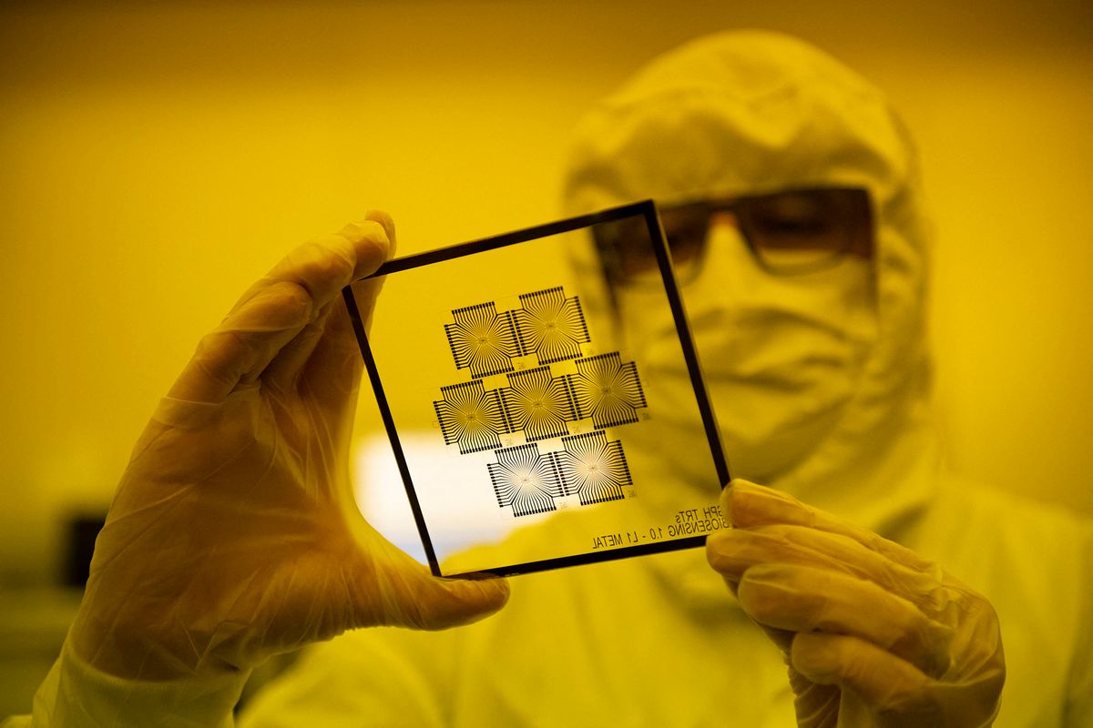 An employee works in the chip manufacturing process at a clean room of the Barcelona Institute for Microelectronics (IMB-CNM) in Bellaterra, near Barcelona, on March 3, 2022. - The Institute of Microelectronics of Barcelona (IMB-CNM) is the largest institute in Spain dedicated to the research and development of Micro and Nano Technology (MNTs) and microsystems, and with unique capacities of silicon semiconductor technology. It belongs to the Spanish National Research Council (CSIC) since its foundation in 1985. (Photo by Josep LAGO / AFP)