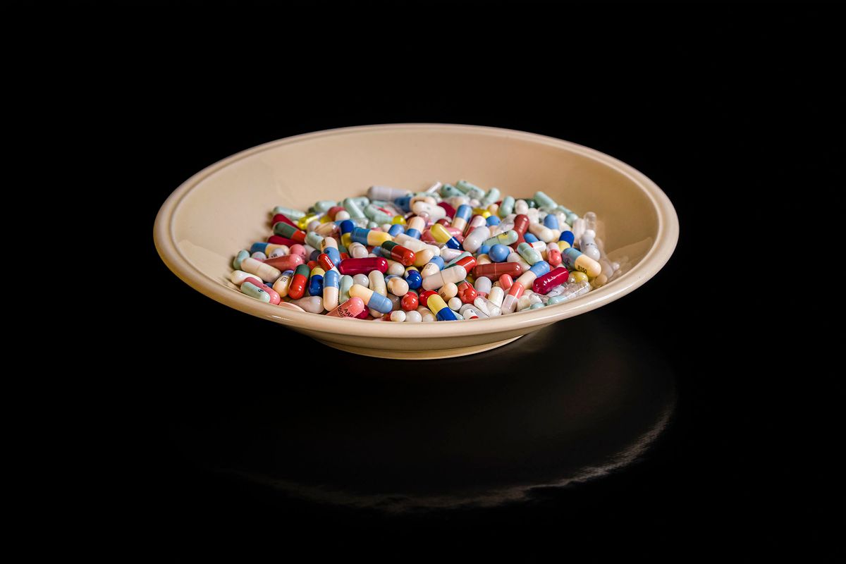 1212168455 GERMANY - 2020/04/30: In this photo illustration a dinner plate filled with differently colored medical capsules, is displayed on a black table. (Photo Illustration by Frank Bienewald/LightRocket via Getty Images)