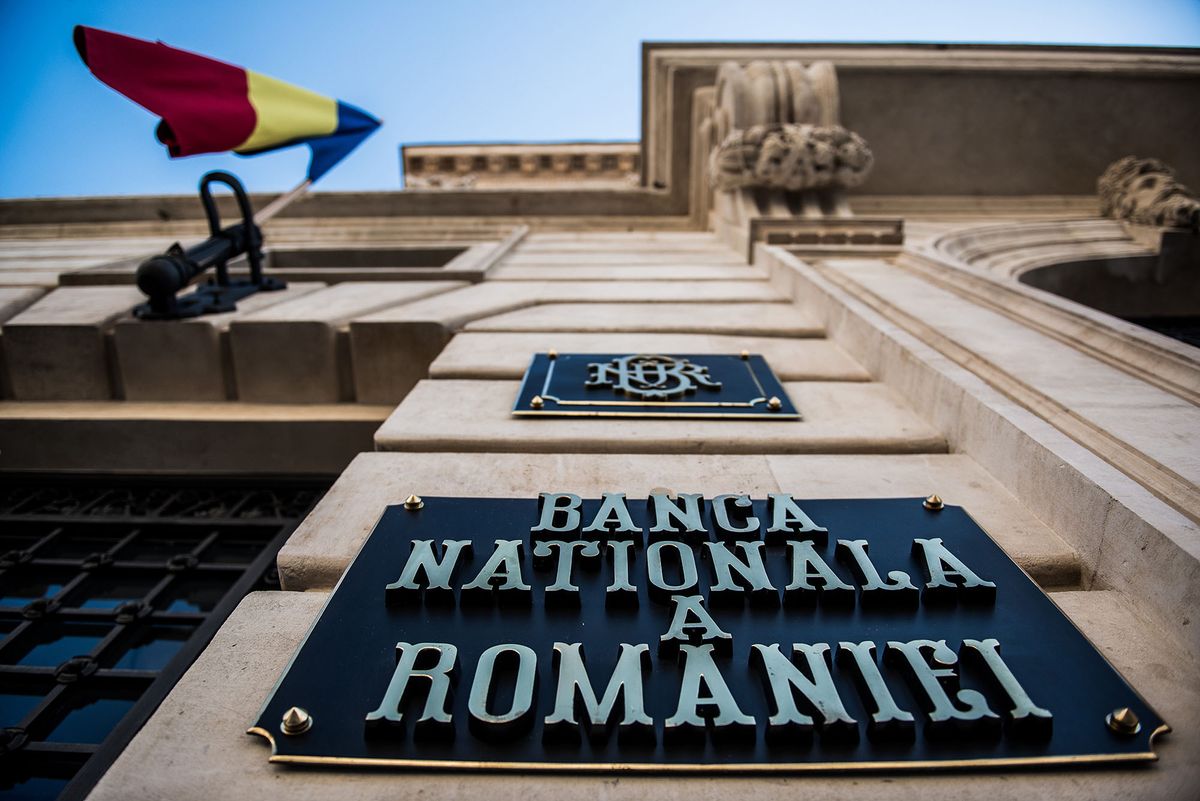 A Romanian national flag flies above a sign outside the entrance to the headquarters of Romania's central bank in Bucharest, Romania, on Thursday, June 12, 2014. For Romania, the events in Crimea across the Black Sea make the crisis "more intense" than for countries in other parts of the continent, the country's Prime Minister Victor Ponta said. Photographer: Akos Stiller/Bloomberg via Getty Images 450546142