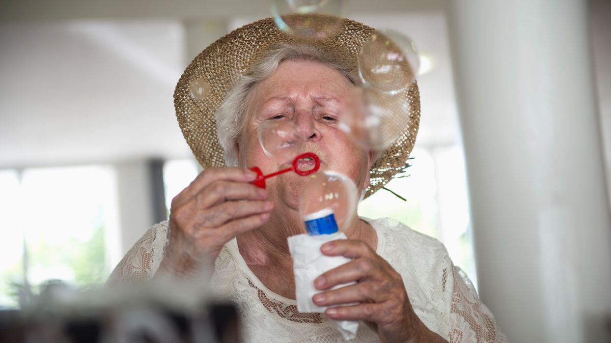 Senior woman blowing bubbles at rest home