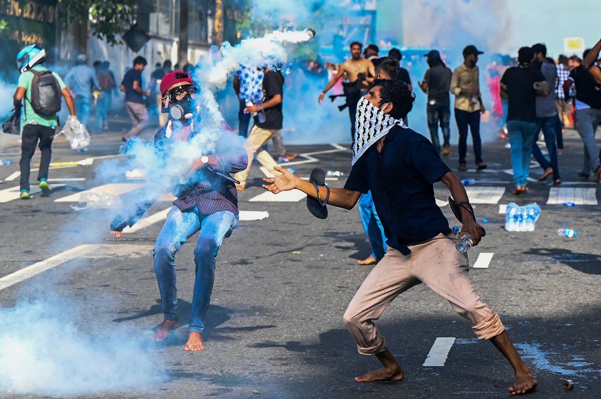 A demonstrator throws back a tear gas canister fired by the police to disperse university students protesting to demand the resignation of Sri Lanka's President Gotabaya Rajapaksa over the country's crippling economic crisis, in Colombo on May 19, 2022. (Photo by ISHARA S. KODIKARA / AFP)