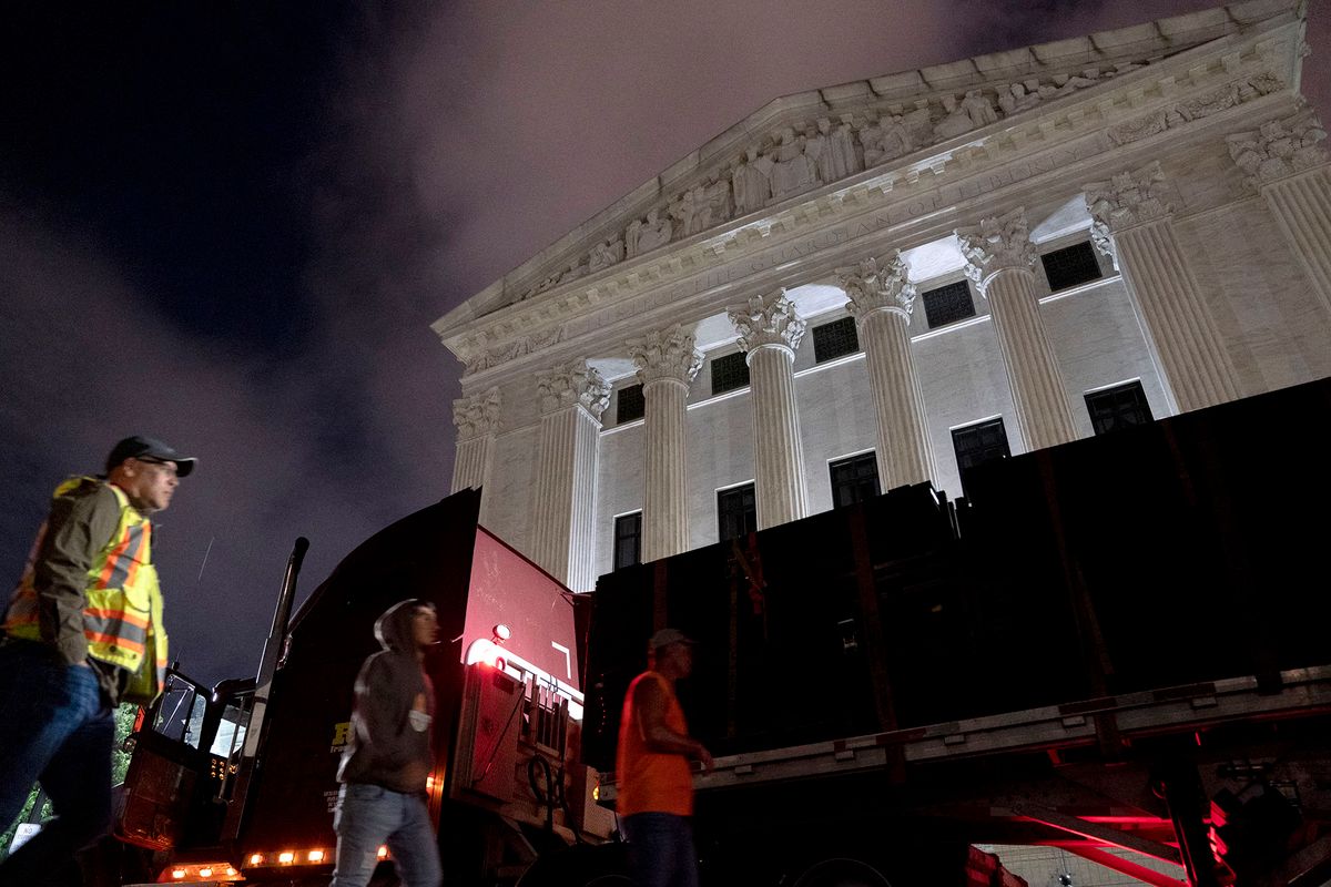 Workers walk past a truck loaded with un-scalable fencing outside the US Supreme Court in Washington, DC, on May 4, 2022. - The fencing is being set up around the Court due to the protests that have occurred in response to the leaked draft of a majority opinion that would shred nearly 50 years of constitutional protections. The draft, obtained by Politico, was written by Justice Samuel Alito, and has been circulated inside the conservative-dominated court, the news outlet reported. Politico stressed that the document it obtained is a draft and opinions could change. The court is expected to issue a decision by June. The draft opinion calls the landmark 1973 Roe v Wade decision "egregiously wrong from the start." (Photo by Stefani Reynolds / AFP)