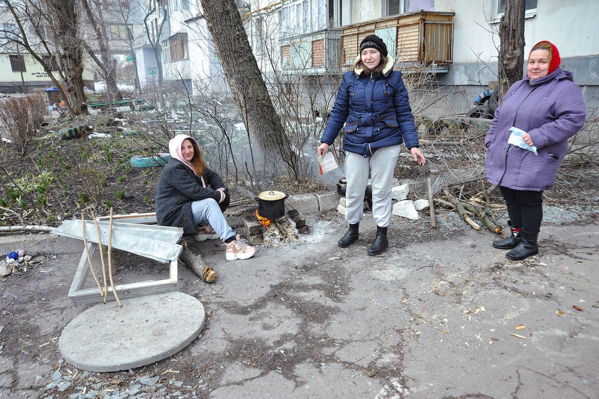 SIEVIERODONETSK, UKRAINE - MARCH 14, 2022 - Women cook food on an open fire in the street as the city remains without electricity and heat supply since March 5th, Sievierodonetsk, Luhansk Region, eastern Ukraine (Photo by Albert Koshelev/Ukrinform/NurPhoto) (Photo by Albert Koshelev / NurPhoto / NurPhoto via AFP)