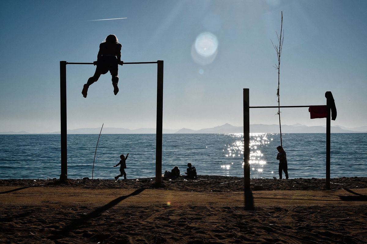 People enjoy sunshine and leisure at a beach in Athens on January 1, 2018. (Photo by LOUISA GOULIAMAKI / AFP)