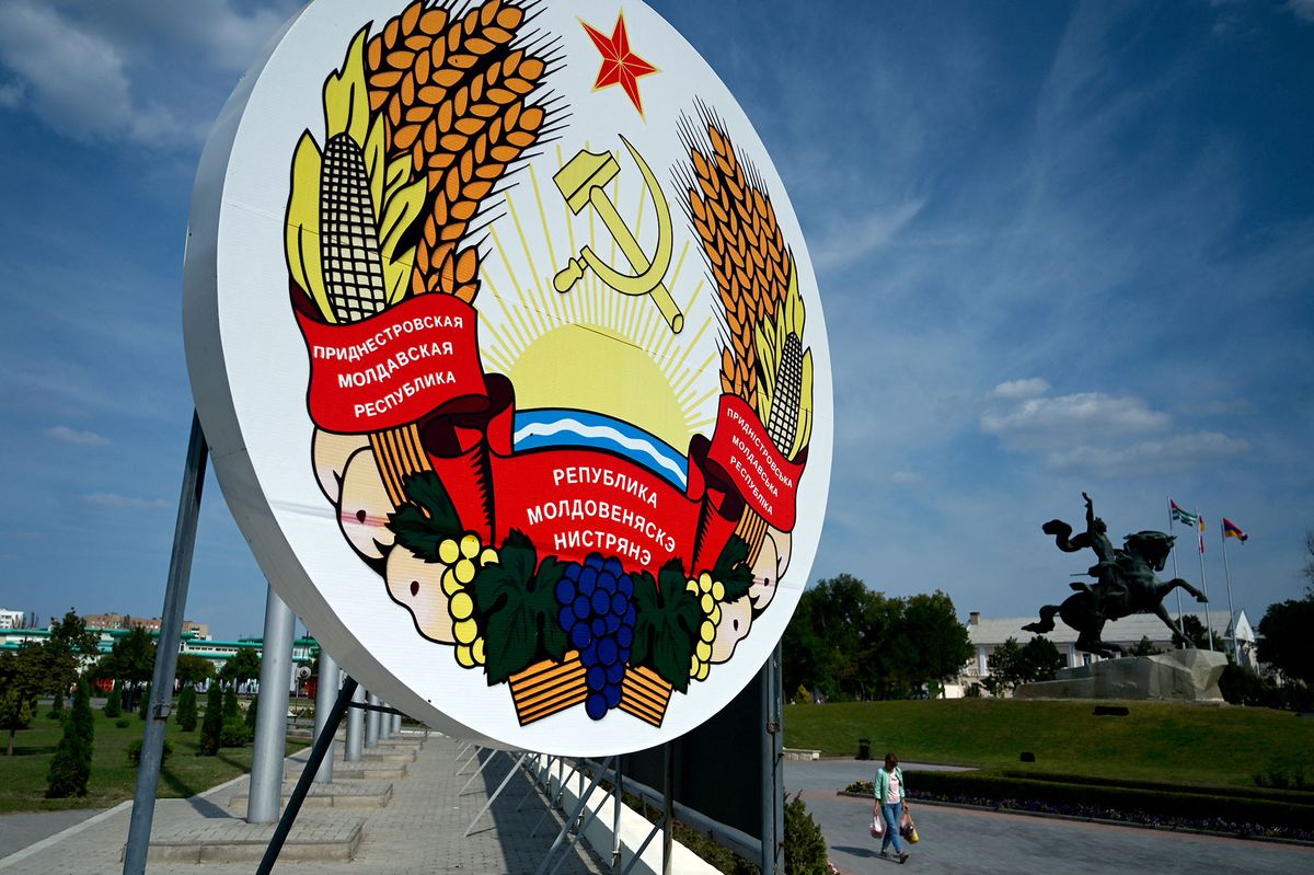 (FILES) In this file photo taken on September 11, 2021 a woman walks past a huge coat of arms of Transnistria - Moldova's pro-Russian breakaway region on the eastern border with Ukraine, in Transnistria's capital of Tiraspol. - The president of ex-Soviet Moldova on April 26, 2022 convened a meeting of the country's security council after a series of blasts in the Russian-backed separatist Transnistria region. The breakaway region of ex-Soviet Moldova, which borders western Ukraine, saw explosions hit its security ministry on Monday and a radio tower on Tuesday morning. The incidents come after a senior Russian military official last week raised the issue of "oppression" of Russian speakers in Transnistria in the context of Russia's military campaign in Ukraine. (Photo by Sergei GAPON / AFP)