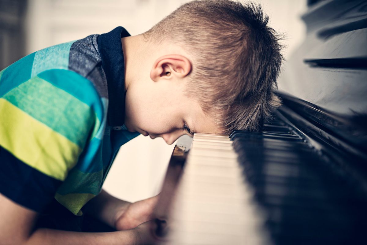 gyerekek is aggódnak a jövőjük miatt 664986900 Angry and frustrated little boy is leaning on his piano keyboard with resignation. Candid, natural portrait, very shallow depth of field. The doy is overworked and depressed.