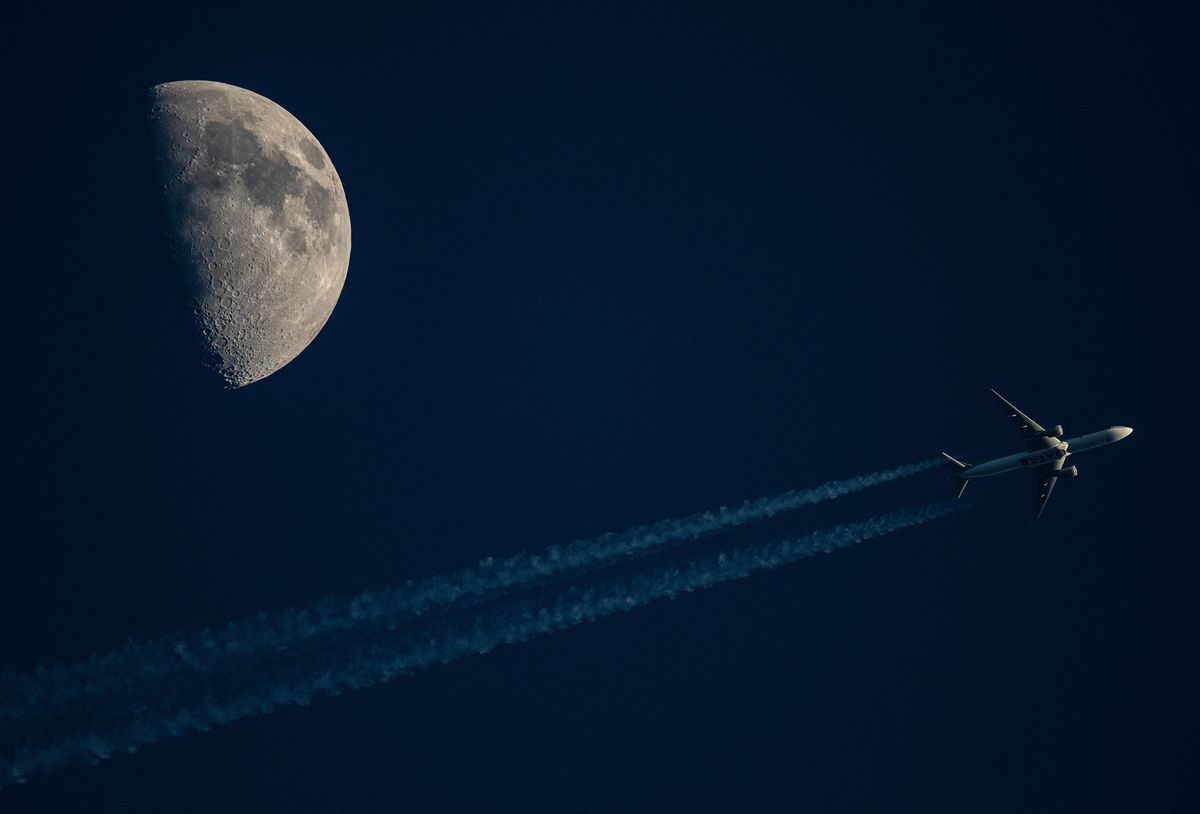 09 May 2022, Hessen, Frankfurt/Main: A Qatar Airways passenger plane passes in front of the moon high in the evening sky. The nights are expected to remain clear with mild temperatures in the coming days. Photo: Boris Roessler/dpa (Photo by BORIS ROESSLER / DPA / dpa Picture-Alliance via AFP)