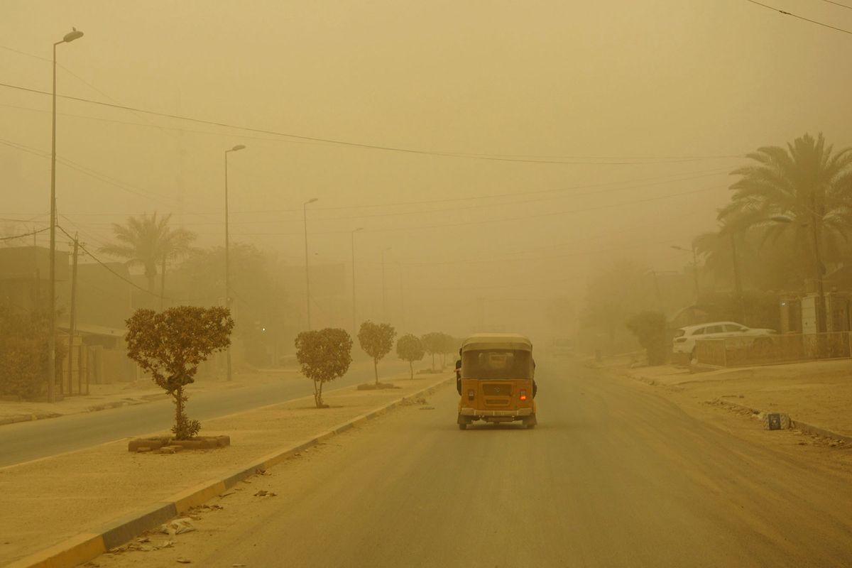 A picture taken on May 5, 2022 shows a car driving through another Spring sandstorm in the Iraqi capital Baghdad. - Iraq is yet again covered in a thick sheet of orange as it suffers the latest in a series of dust storms that have become increasingly common. Iraq was hammered by a series of such storms in April, grounding flights and leaving dozens hospitalised with respiratory problems. (Photo by Sabah ARAR / AFP)