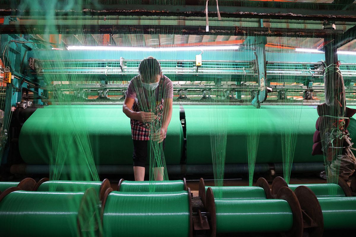 A worker produces fiber netting at a factory in Binzhou in China's eastern Shandong province on May 31, 2022. (Photo by AFP) / China OUT