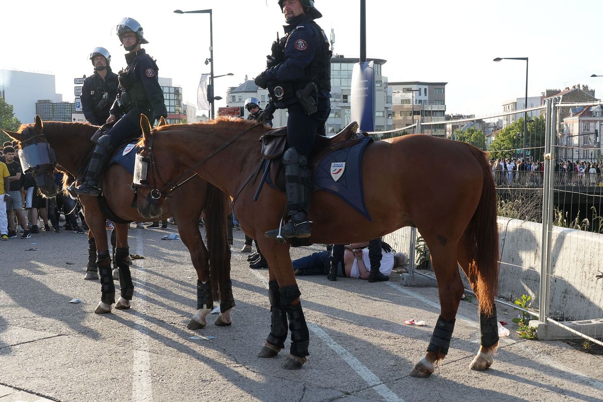 1399787717 PARIS, FRANCE - MAY 28: A man is arrested by riot police on horses as Spanish fans gather near Stade de France prior the  UEFA Champions League Final Between Liverpool and Real Madrid on May 28, 2022 in Saint-Denis, near, Paris, France. (Photo by Sylvain Lefevre/Getty Images)