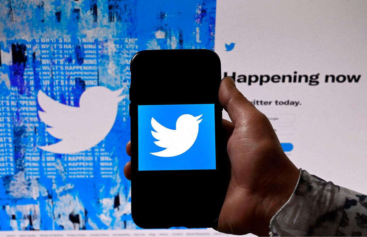 In this photo illustration, a phone screen displays the Twitter logo on a Twitter page background, in Washington, DC, on April 26, 2022. - Billionaire Elon Musk is capturing a social media prize with his deal to buy Twitter, which has become a global stage for companies, activists, celebrities, politicians and more. (Photo by Olivier DOULIERY / AFP)