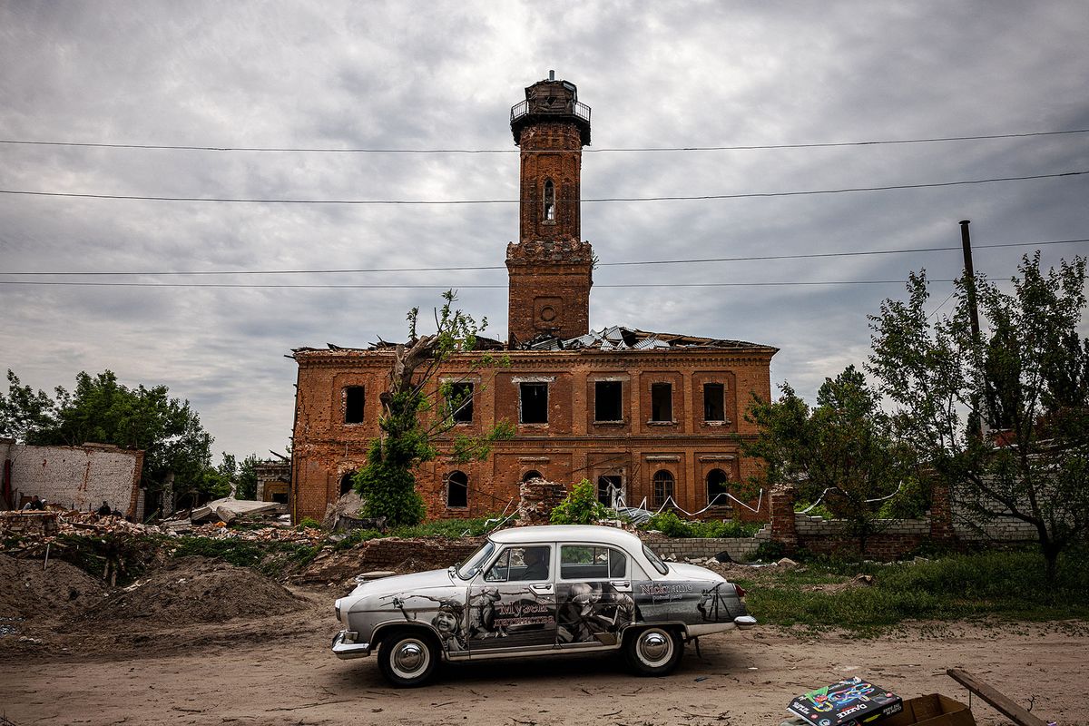 A man drives a GAZ-21 Volga car past a damaged building in Kharkiv, eastern Ukraine, on May 26, 2022, on the 92nd day of the Russian invasion of Ukraine. (Photo by Dimitar DILKOFF / AFP)
