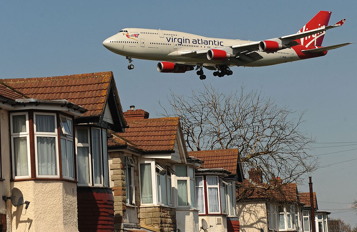 A Virgin Atlantic passenger jet flies over houses as it prepares to land at Heathrow Airport in west London on April 21, 2010.   Europe's airspace reopened for business as Iceland's volcano lost its fury Wednesday, leaving passengers scrambling to get home and recriminations flying over the 1.7 billion dollar cost of the crisis.         AFP PHOTO/BEN STANSALL (Photo by BEN STANSALL / AFP)