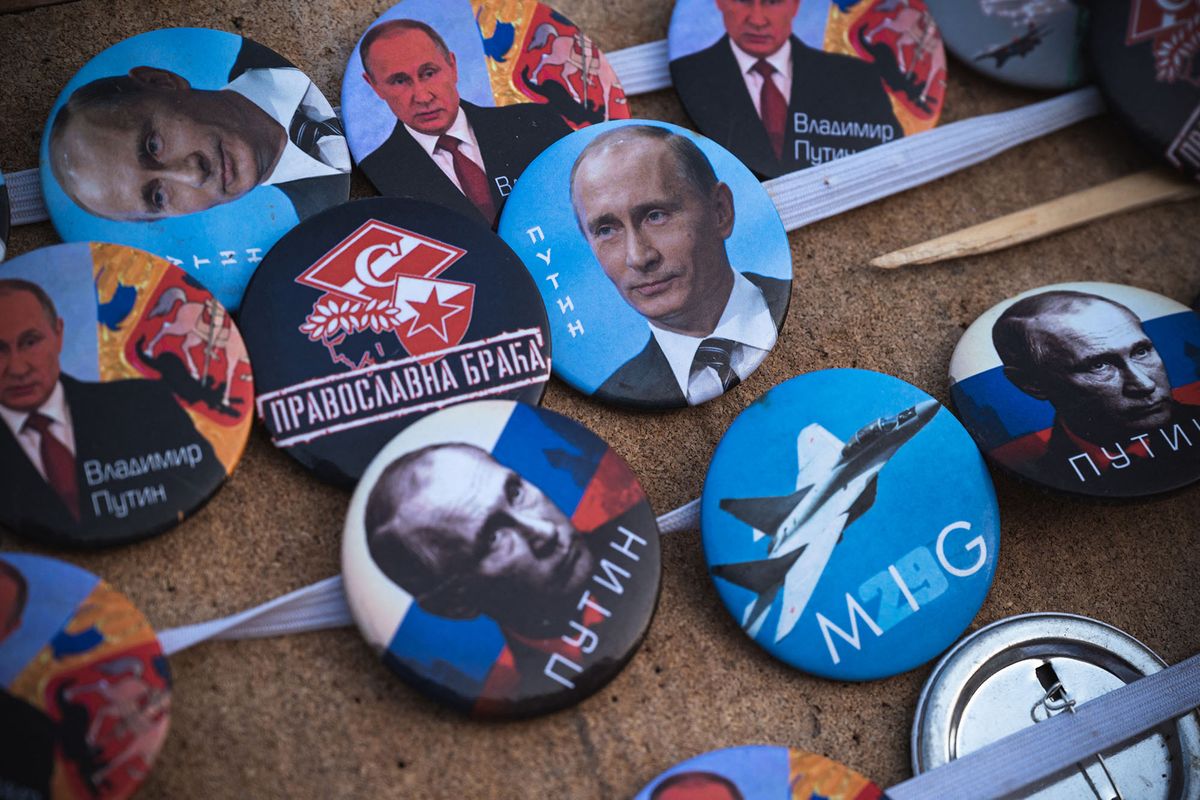 A street vendor sales badges depicting Russian President Vladimir Putin during a rally organised by Serbian ultra nationalists organisations in Belgrade on April 15, 2022, to protest against the Serbian authorities for voting to suspend Russia's membership in the UN Human Rights Council. (Photo by Andrej ISAKOVIC / AFP)