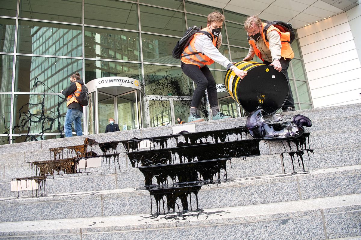 11 April 2022, Hessen, Frankfurt/Main: Demonstrators dump black colored water during a protest by the group "Last Generation" at Commerzbank headquarters. The group is calling for an immediate halt to all investment in and new expansion of fossil fuel infrastructure. Photo: Sebastian Gollnow/dpa (Photo by Sebastian Gollnow / DPA / dpa Picture-Alliance via AFP)