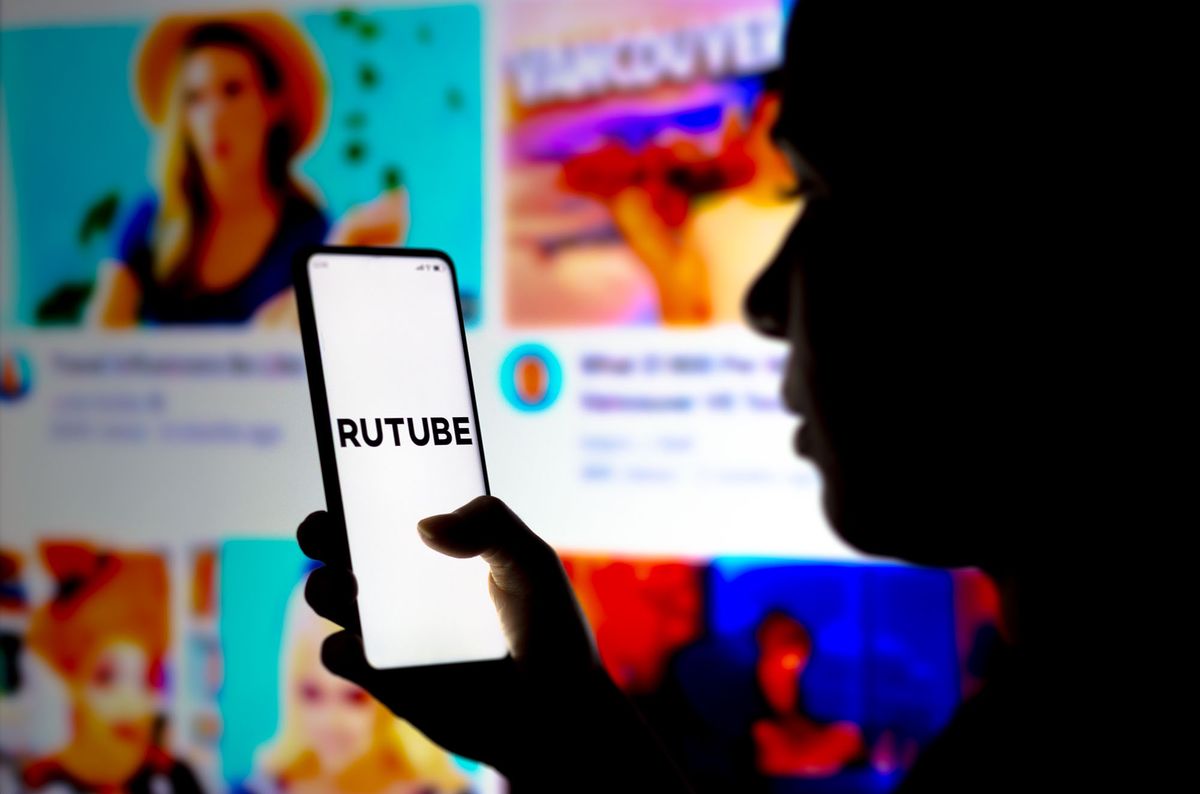 BRAZIL - 2022/03/23: In this photo illustration, a woman's silhouette holds a smartphone with the RUTUBE logo displayed on the screen. (Photo Illustration by Rafael Henrique/SOPA Images/LightRocket via Getty Images) 1239457672
