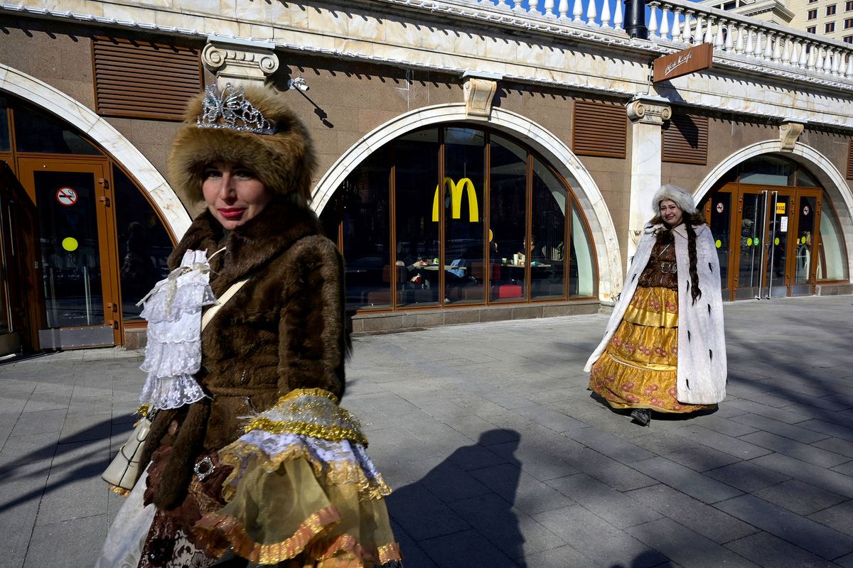 Women walk in front of a McDonald's restaurant in central Moscow on March 9, 2022. - McDonald's, Coca-Cola and Starbucks on March 8, 2022 bowed to public pressure and suspended their operations in Russia, joining the international corporate chorus of outrage over Moscow's invasion of Ukraine. Several of these companies, symbols of American cultural influence in the world, have been the subject of boycott calls on social media as investors have also begun to ask questions about their presence. (Photo by AFP)