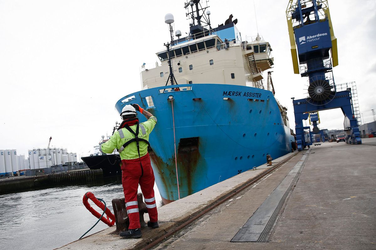 A Peterson Ltd. employee throws off a mooring line as the anchor handling tug supply ship Maersk Assister, operated by A.P. Moeller-Maersk A/S, prepares to depart from Aberdeen Harbour, operated by the Aberdeen Harbour Board, in Aberdeen, U.K., on Friday, Aug. 8, 2014. The oil and gas industry remains central to the debate on Scotland's independence ahead of the forthcoming Sept. 18 referendum. Photographer: Simon Dawson/Bloomberg via Getty Images 453483142