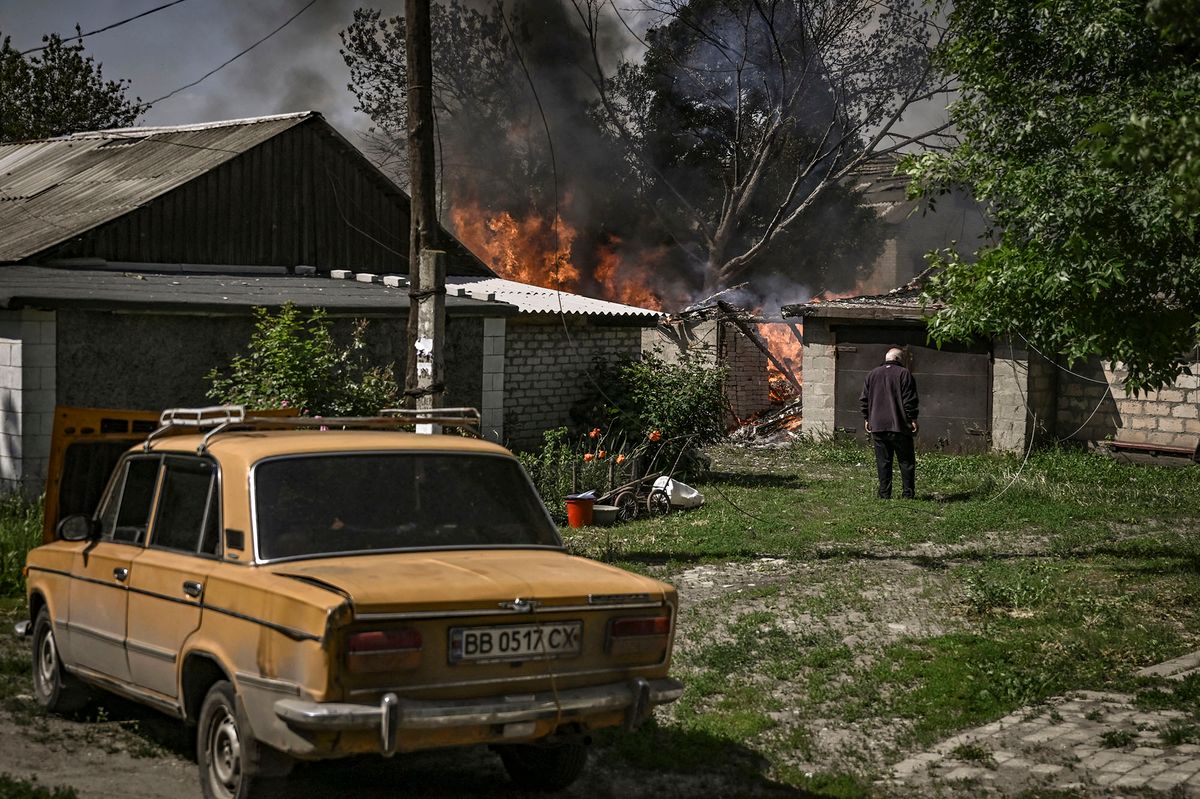 An elderly man stands in front of a burning house garage after shelling in the city of Lysytsansk at the eastern Ukrainian region of Donbas on May 30, 2022, on the 96th day of the Russian invasion of Ukraine. - Since failing to capture Kyiv in the war's early stages, Russia's army has narrowed its focus, hammering Donbas cities with artillery and missile barrages as it seeks to consolidate its control. (Photo by ARIS MESSINIS / AFP)