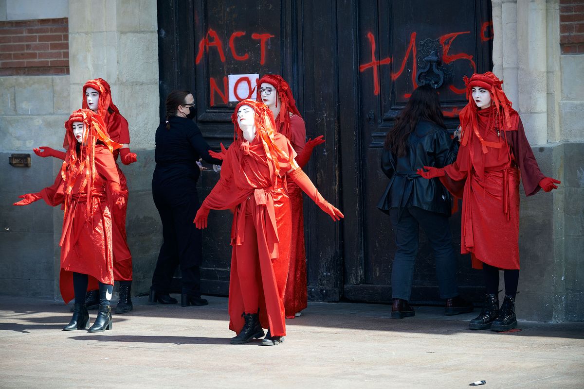 Protesters paint on the gates of the townhall of toulouse 'Act NOW' and '+1.5∞C = death'. XR (Extinction Rebellion) organized in Toulouse an happening to call out French presidential candidates to take into consideration the climate emergency, which is nearly absent from the political campaign. The theme was 'Our house is burning, and politicians look elsewhere'. For this happening, some were dresse in red, other disguised in pregnant women to symbolize the death of future generations due to global warming and envionmental collapse.They also did a die-in in front of the townhall of Toulouse.  Toulouse. France. March 26th 2022. (Photo by Alain Pitton/NurPhoto) (Photo by Alain Pitton / NurPhoto / NurPhoto via AFP)