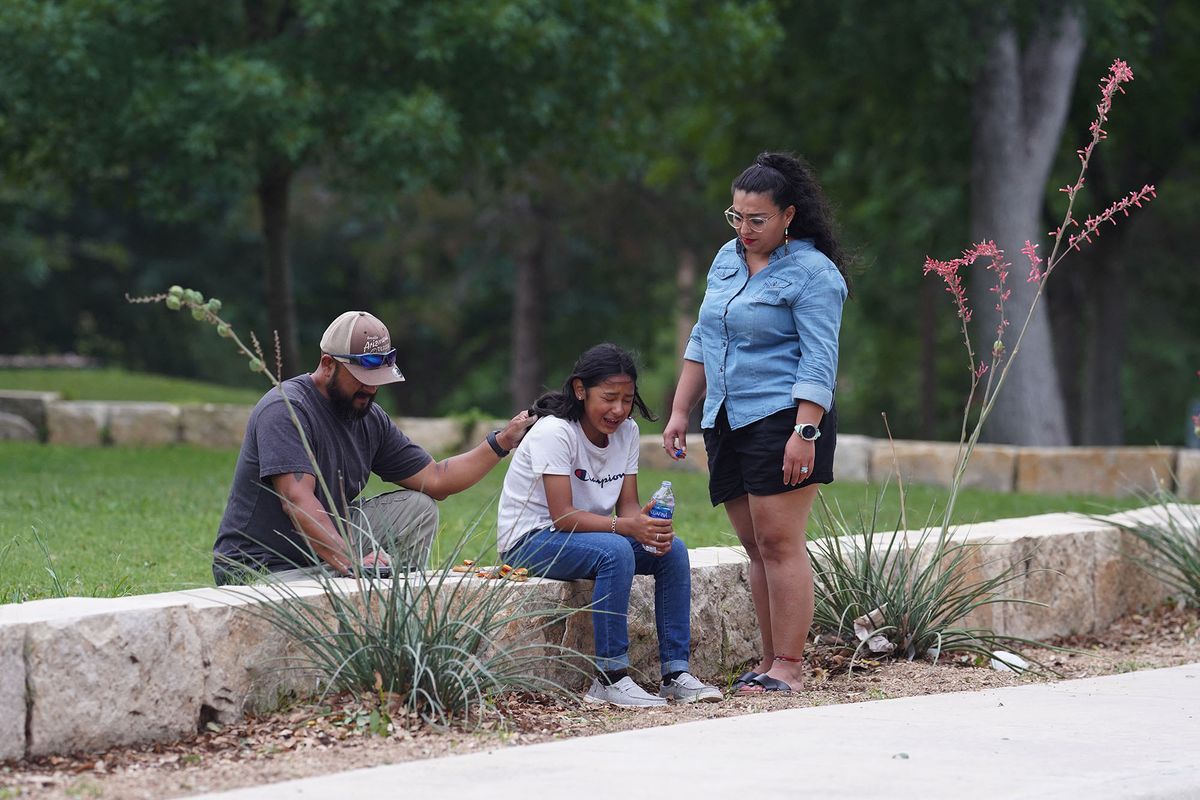 A girl cries, comforted by two adults, outside the Willie de Leon Civic Center where grief counseling will be offered in Uvalde, Texas, on May 24, 2022. - A teenage gunman killed 18 young children in a shooting at an elementary school in Texas on Tuesday, in the deadliest US school shooting in years.The attack in Uvalde, Texas -- a small community about an hour from the Mexican border -- is the latest in a spree of deadly shootings in America, where horror at the cycle of gun violence has failed to spur action to end it. (Photo by allison dinner / AFP)