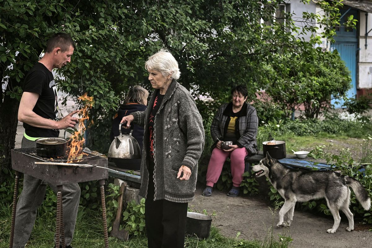 Residents of the city of Lysychansk cook food outside their houses, as the city is without electricity and water, in the eastern Ukrainian region of Donbas, on May 26, 2022, amid Russia's military invasion launched on Ukraine. - Ukraine said may 26 the war in the east of the country had hit its fiercest level yet as it urged Western allies to match words with support against invading Russian forces. Moscow's troops are pushing into the industrial Donbas region after failing to take the capital Kyiv, closing in on several urban centres including the strategically located Severodonetsk and Lysychansk. (Photo by ARIS MESSINIS / AFP)