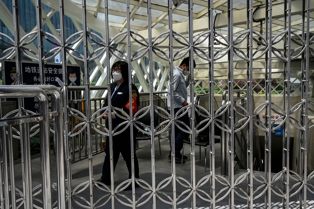 A subway staff member stands guard at the entrance of a closed subway station in the central business district in Beijing on May 4, 2022. - Beijing closed dozens of subway stations on May 4, as Covid restrictions slowly constrict movement across the Chinese capital of over 21 million people. (Photo by Jade GAO / AFP)