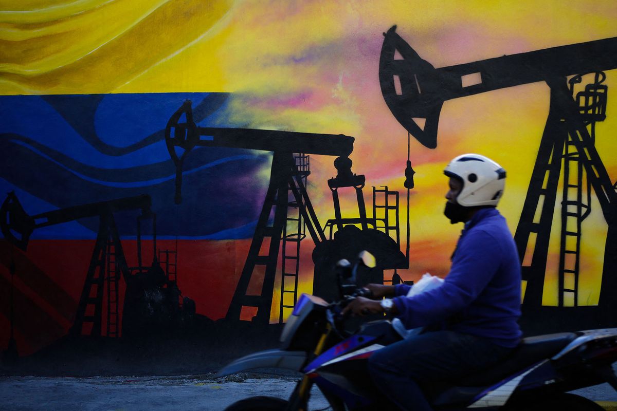 A motorcycle passes in front of an oil-themed mural in Caracas, Venezuela on May 9, 2022. (Photo by Javier Campos/NurPhoto) (Photo by Javier Campos / NurPhoto / NurPhoto via AFP)