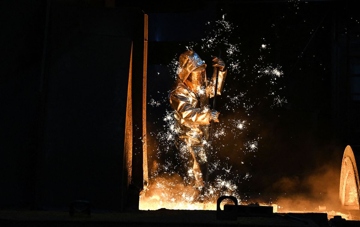 Sparks fly as an employee takes a sample at the blast furnace at the ThyssenKrupp plant in Duisburg, western Germany on November 16, 2021. - Shares in Thyssenkrupp rose at the Frankfurt Stock Exchange on November 16 after press reports about the possible IPO of a unit developing green hydrogen projects. ThyssenKrupp wants to find out, how coal can be replaced by hydrogen in the production of iron in their blast furnaces. Behind this is the "H2Stahl" project, the aim of which is to reduce CO2 emissions in steel production in the future by using hydrogen. (Photo by Ina FASSBENDER / AFP)