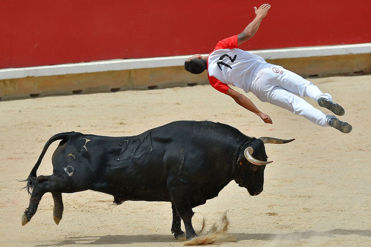An acrobat jumps over a bull during a bull-leaping show at the San Fermin festival in Pamplona, northern Spain, on July 12, 2019. - People from around the world flock to the city of 200,000 residents to test their bravery and enjoy the festival's mix of round-the-clock parties, religious processions and concerts. (Photo by ANDER GILLENEA / AFP)