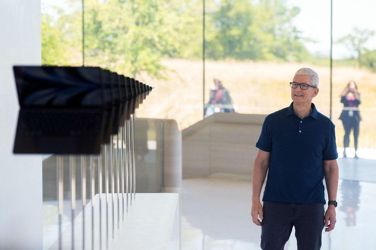 Apple CEO Tim Cook walks along a line of new MacBook Air computers as he enters the Steve Jobs Theater during the 2022 Apple Worldwide Developers Conference (WWDC), on June 6, 2022 at the Apple Park campus in Cupertino, California. (Photo by Chris Tuite / AFP)