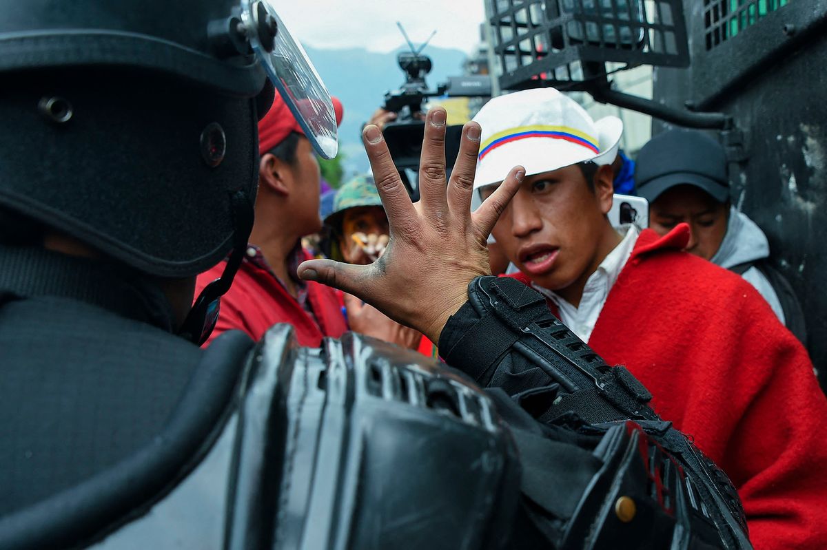 A police officer gestures as he talks to indigenous people gathering in the El Arbolito park area in Quito, on June 22, 2022, on the tenth consecutive day of indigenous-led protests against the Ecuadorean government. - An indigenous protester died on Tuesday in clashes with law enforcement during indigenous-led fuel price protests that have triggered regional states of emergency and a curfew in the capital Quito. (Photo by Rodrigo BUENDIA / AFP)