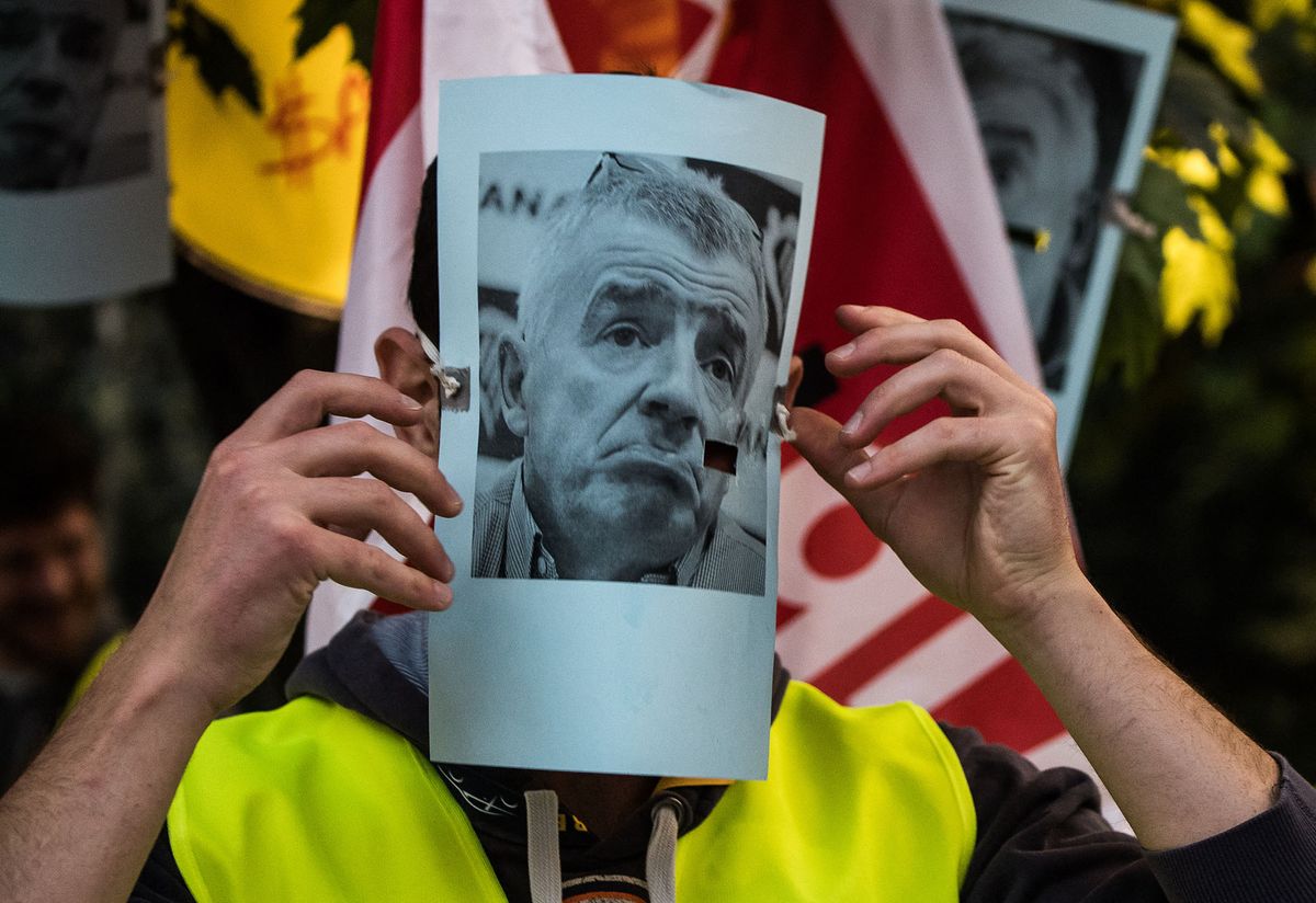 28 September 2018, Hessen, Frankfurt_Main: A striking flight attendant puts on a mask showing the portrait of Michael Kevin O'Leary, Chairman of Ryanair. The employee does not want to show himself because he expects consequences from his employer. Trade unions in several European countries have called for strikes at low-cost airline Ryanair. In Germany, the pilots of the Cockpit Association (VC) and the flight attendants organized at Verdi participate. Photo: Andreas Arnold/dpa (Photo by Andreas Arnold / DPA / dpa Picture-Alliance via AFP)