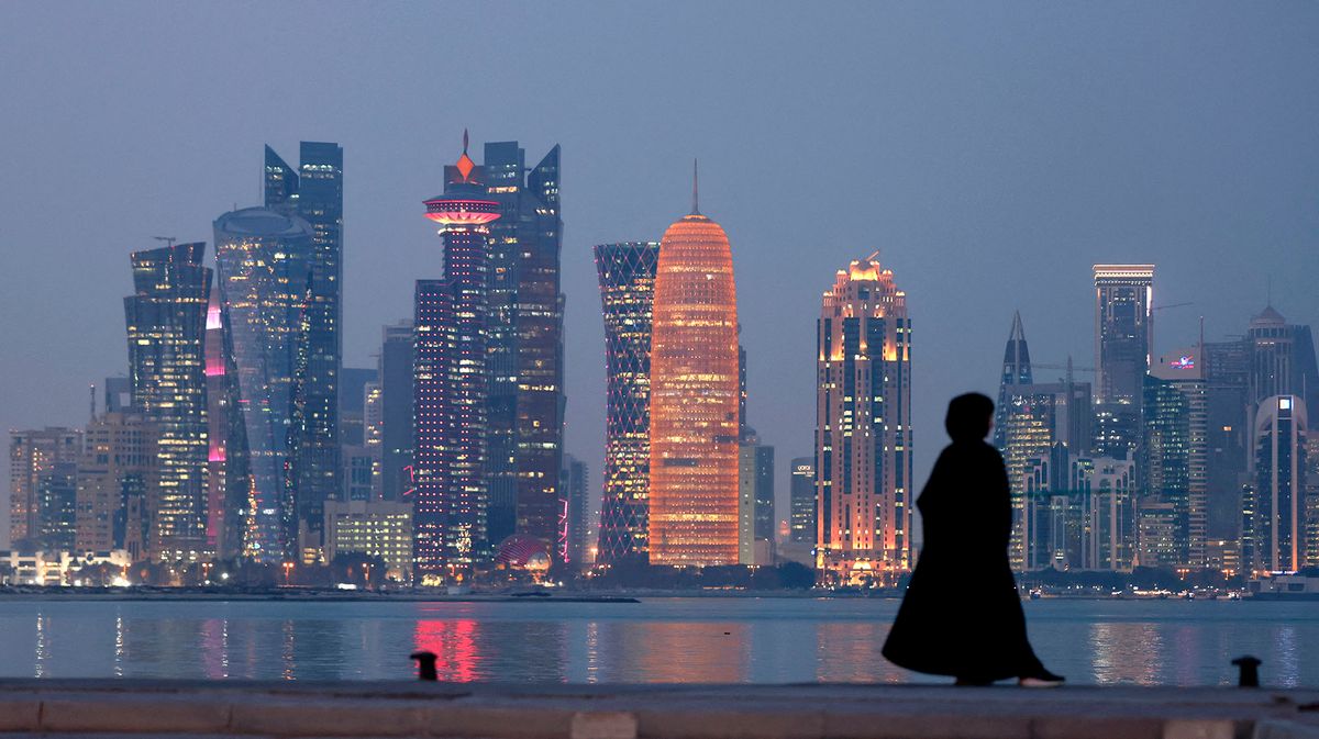 A woman stands by the waterfront overlooking the towered skyline of Qatar's capital Doha on December 13, 2021. (Photo by Karim SAHIB / AFP)