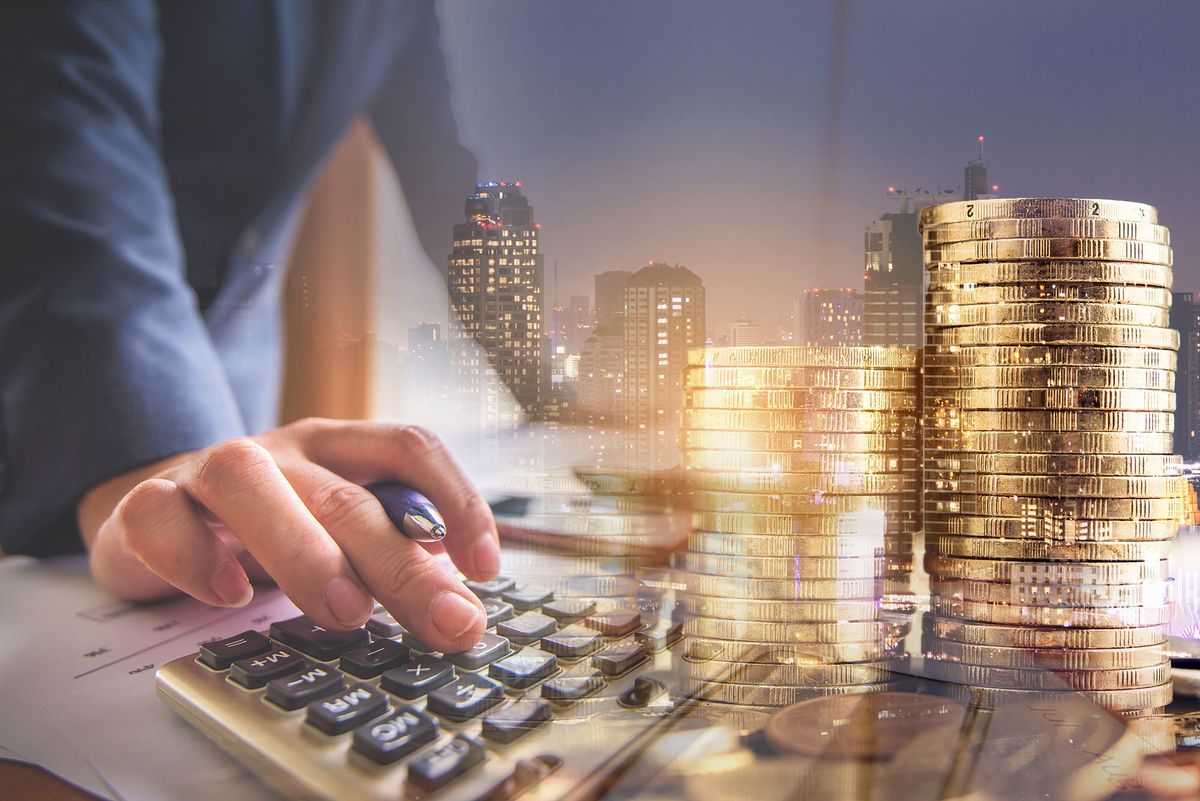 double exposure of businessman working with calculator at office with step of golden coins and city night 