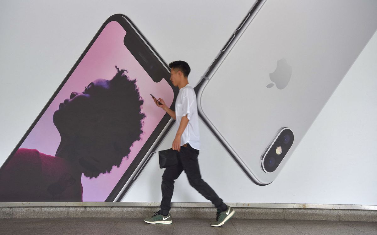 --FILE--A passenger walks past an advertisement for Apple's iPhone XS smartphones in Shanghai, China, 11 December 2018.Apple Inc. Wednesday cut its revenue expectations for the most recent quarter, citing slower sales in China. The iPhone maker estimated revenue of about $84 billion for the quarter ended Dec. 29, down from a previous projection of $89 billion to $93 billion. In a letter to investors, Apple Chief Executive Officer Tim Cook attributed the reduction to a slowdown in the Greater China region, which accounts for almost 20% of its revenue. "Most of our revenue shortfall to our guidance, and over 100% of our year-over-year worldwide revenue decline, occurred in Greater China across iPhone, Mac and iPad," Cook said. The announcement further fueled concerns over the tech giant's growth outlook, especially under the shadow of the trade war between China and the U.S. Several of Apple's suppliers, including the biggest one, Foxconn Technology Group, have announced cost cuts due to gloomy projections for iPhone sales. (Photo by Xu hede / Imaginechina / Imaginechina via AFP)