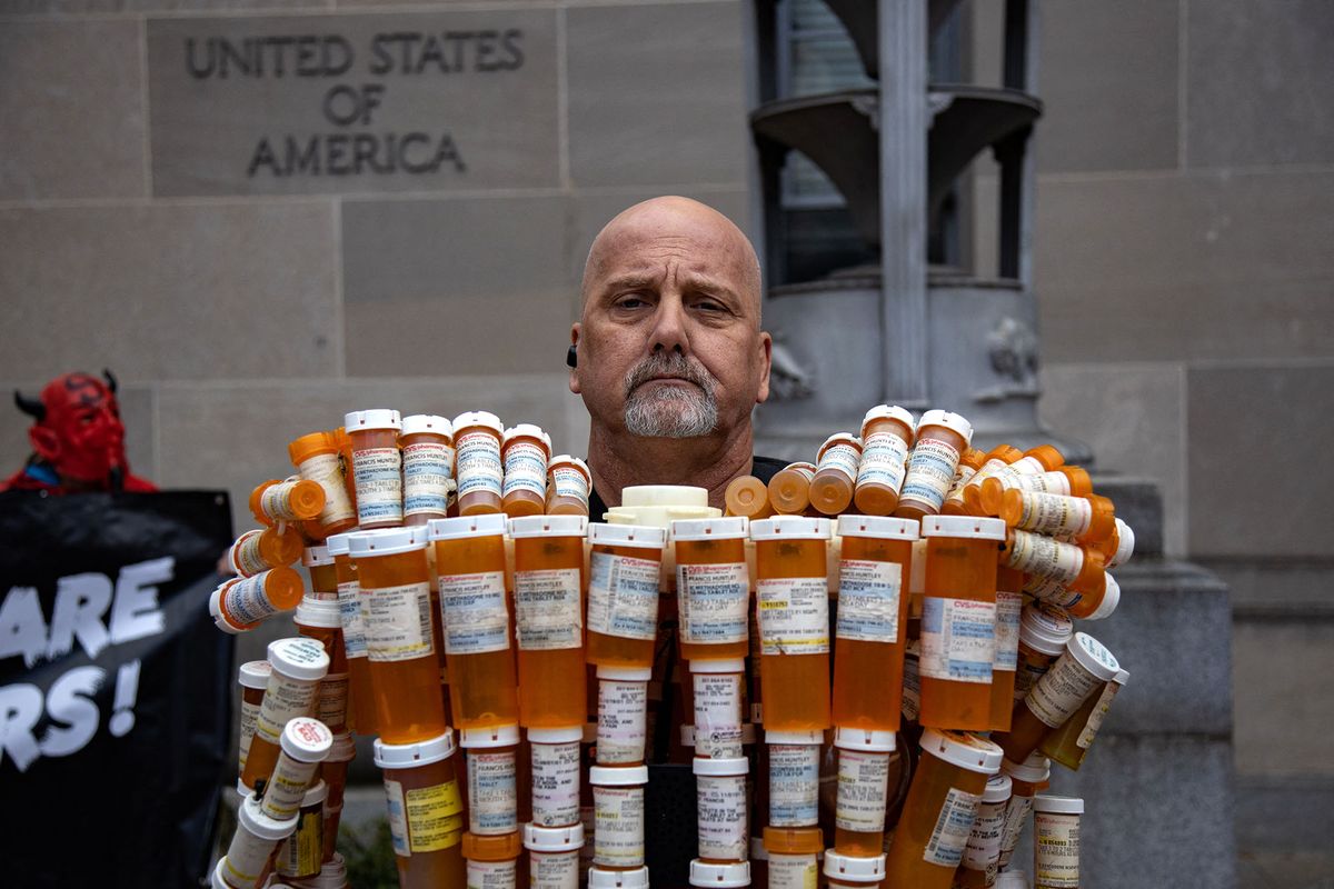 Frank Huntley, also known as the &quot;Pill Man&quot;, stands behind his sculpture in front of the Department of Justice building in Washington, D.C. on December 3, 2021 during a protest. The life-size sculpture is made of his own opioid prescription pill bottles of which he was addicted to. (Photo by Bryan Olin Dozier/NurPhoto) (Photo by Bryan Olin Dozier / NurPhoto / NurPhoto via AFP)