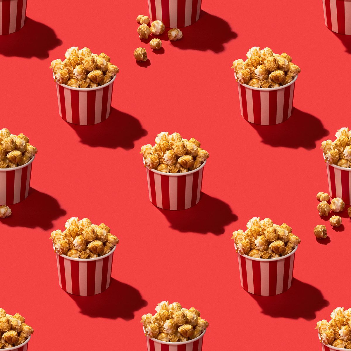 Popcorn in striped paper box on red background seamless pattern stock photo