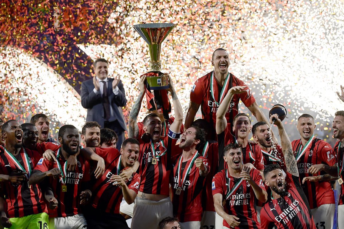 AC Milan's Italian defender Alessio Romagnoli (C-L with throphy), AC Milan's Swedish forward Zlatan Ibrahimovic (Top R), AC Milan's French forward Olivier Giroud (Bottom R) and AC Milan's players celebrate with the winner's trophy after AC Milan won the Italian Serie A football match between Sassuolo and AC Milan, securing the "Scudetto" championship on May 22, 2022 at the Mapei - Citta del Tricolore stadium in Sassuolo. (Photo by Filippo MONTEFORTE / AFP)