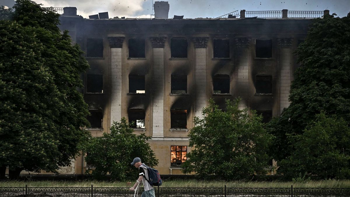 A man walks past a burning college after a strike in Lysychansk, eastern Ukrainian region of Donbas on June 7, 2022. (Photo by ARIS MESSINIS / AFP)