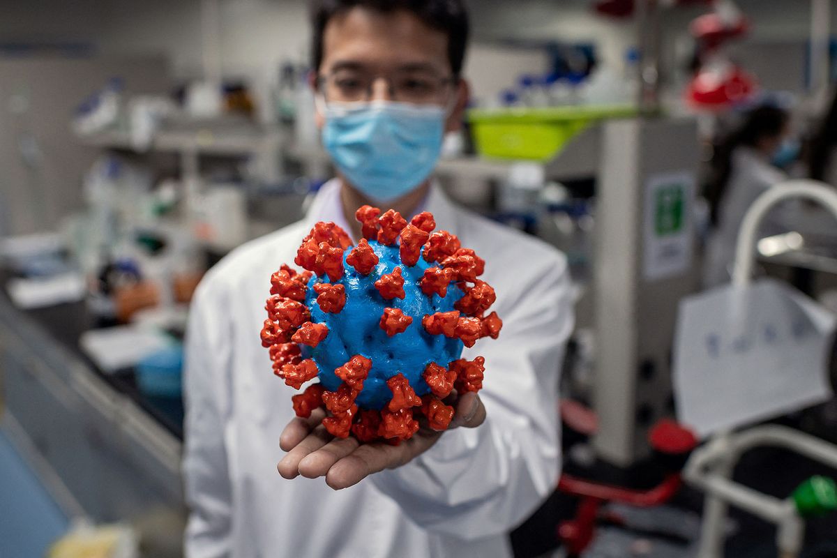 In this picture taken on April 29, 2020, an engineer shows a plastic model of the COVID-19 coronavirus at the Quality Control Laboratory at the Sinovac Biotech facilities in Beijing. - Sinovac Biotech, which is conducting one of the four clinical trials that have been authorised in China, has claimed great progress in its research and promising results among monkeys. (Photo by NICOLAS ASFOURI / AFP)