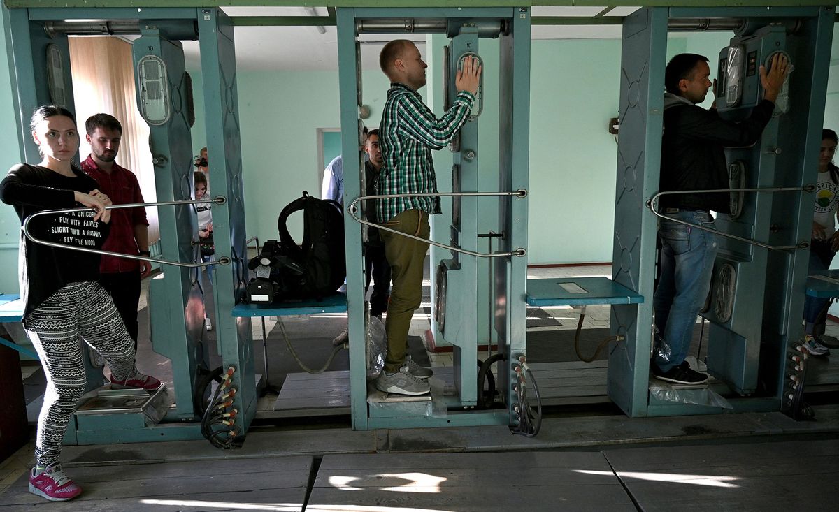 People pass through radiation measuring device during a tour in the Chernobyl exclusion zone on June 7, 2019. - HBOís hugely popular television series ìChernobylî has renewed interest around the world on Ukraineís 1986 nuclear disaster with authorities reporting a 30% increase of tourist demands to visit the affected area and tourist operators forecasting that number of tourists visiting the site may double this year up to 150.000 persons (Photo by Genya SAVILOV / AFP)