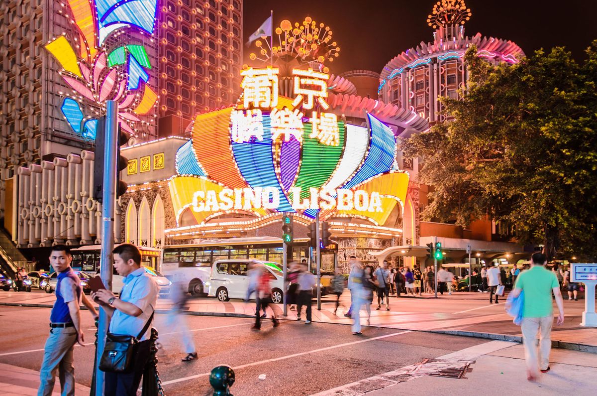 --FILE--Pedestrians walk past the Grand Lisboa casino in Macau, China, 14 June 2014.Macaus casino revenue fell for the first time in five years last month as the World Cup diverted some bettors in the worlds largest gambling hub. Total gross gaming revenue dropped 3.7 percent to 27 billion patacas ($3.4 billion) last month, the first decline since June 2009 when it fell 17 percent, according to Macaus Gaming Inspection and Coordination Bureau. This compared with the median estimate of a 4 percent decline from nine analysts surveyed by Bloomberg News. Casinos in Macau, the only place in China where they Are legal, rely on high rollers brought in by junket operators for more than 60 percent of revenue. Growth in the VIP segment has slowed as gamblers cut spending amid a cooling economy and a nationwide crackdown on corruption in China. (Photo by Xue zheng / Imaginechina / Imaginechina via AFP)