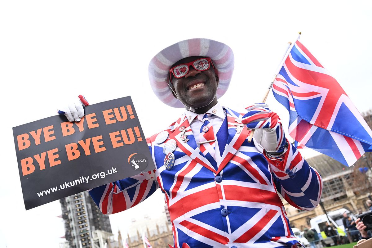 Joseph Afrane, bedecked in Union flag colours, holds up a sign saying "Bye bye EU" on Parliament Square opposite the Houses of Parliament in London on January 31, 2020 on the day that the UK formally leaves the European Union. - Britain on January 31 ends almost half a century of integration with its closest neighbours and leaves the European Union, starting a new -- but still uncertain -- chapter in its long history. (Photo by Glyn KIRK / AFP)