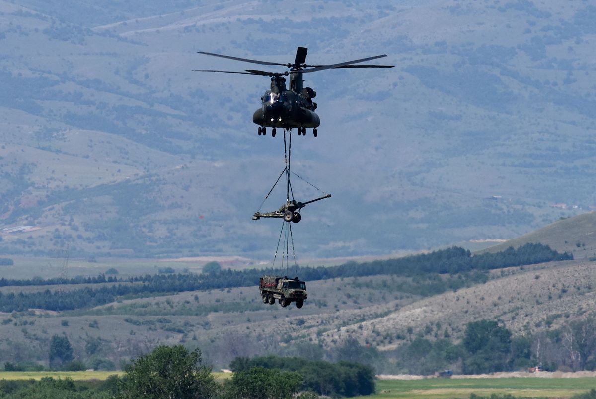A British Chinook helicopter transports a howitzer and a truck during the Swift Response 22 military exercise at the Krivolak Military Training Center in Negotino, in the centre of North Macedonia, on May 12, 2022. - The excercise, which involves approximately 4,600 soldiers from North Macedonia, Albania, Montenegro, Greece, Italy, as well as France, the UK and the US, is meant to show that NATO forces can be deployed around the world and fully cooperate. (Photo by Robert ATANASOVSKI / AFP)