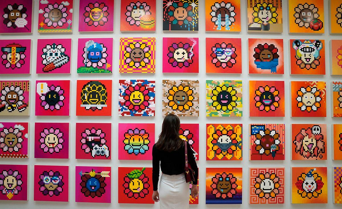 A person stands in front  of artist Takashi Murakamiís NFT project called Murakami Flowers during a press preview May 11, 2022  for ìAn Arrow through Historyî at Gagosianís New York galleries. - This will be Murakami's first exhibition at Gagosian in New York since 2014 and represents his return to 980 Madison Avenue, where he had his inaugural exhibition with the gallery in 2007. (Photo by TIMOTHY A. CLARY / AFP) 