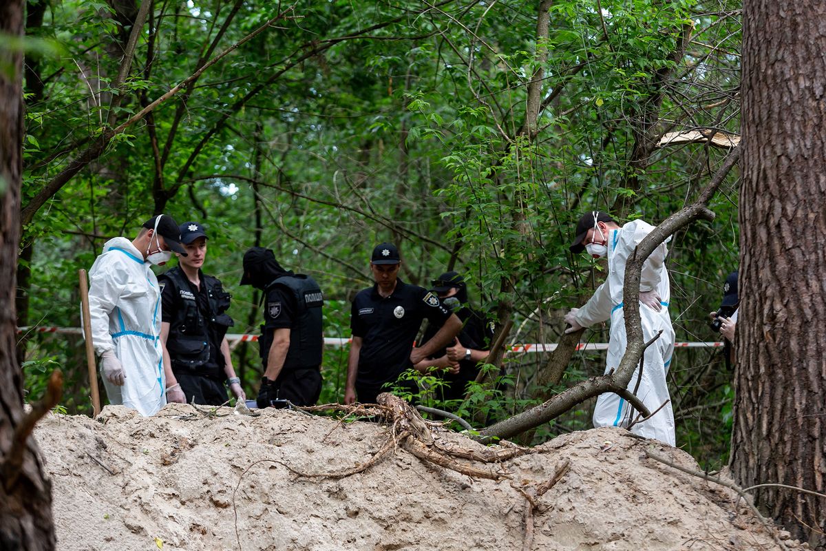 An excavation team and police works in a forest near Bucha, Ukraine to excavate bodies of Ukrainian civilians murdered by Russian army  - June 13, 2022. The bodies were discovered by a patrol of Territorial Defence Forces and were located near tranches built by the Russian army when it occupied the territory. Seven bodies were excavated from a mass grave. Some of the bodies have signs of being tied and  shot at. An investigation will follow. (Photo by Dominika Zarzycka/NurPhoto) (Photo by Dominika Zarzycka / NurPhoto / NurPhoto via AFP)